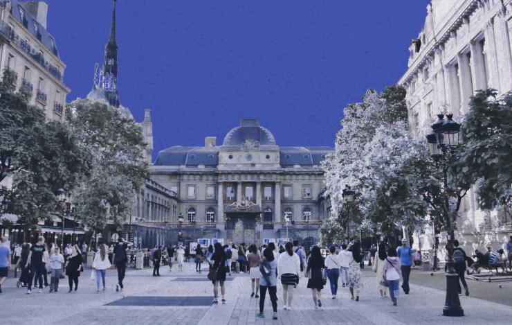 European square with people walking and a historic building, in blue tones.